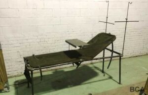 Military field hospital bed with patient table and IV poles
